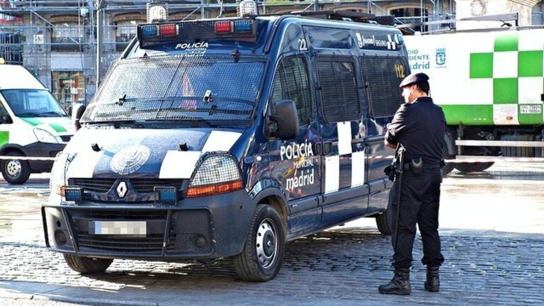 Un agente de la Polic&iacute;a Municipal de Madrid junto a un furg&oacute;n antidisturbios.