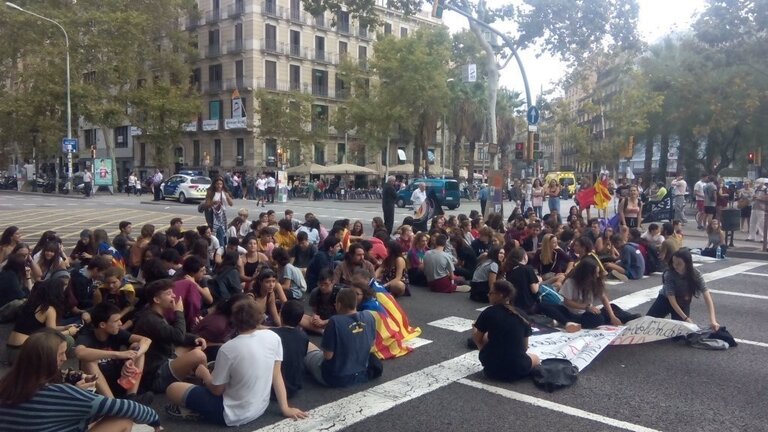 Estudiantes se sientan en la calzada de la Gran V&iacute;a de Barcelona para cortar el tr&aacute;fico.