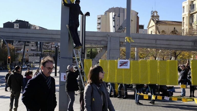 Independentistas colocando pancartas y lazos amarillos en Barcelona.