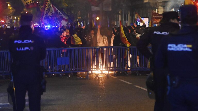 Varias personas queman una bandera estelada, durante la protesta convocada por el sindicato de Vox, en la calle Ferraz de Madrid.