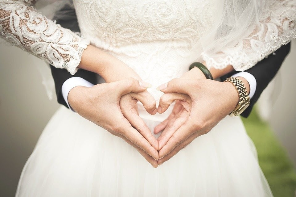 Novios forman un corazón con las manos.