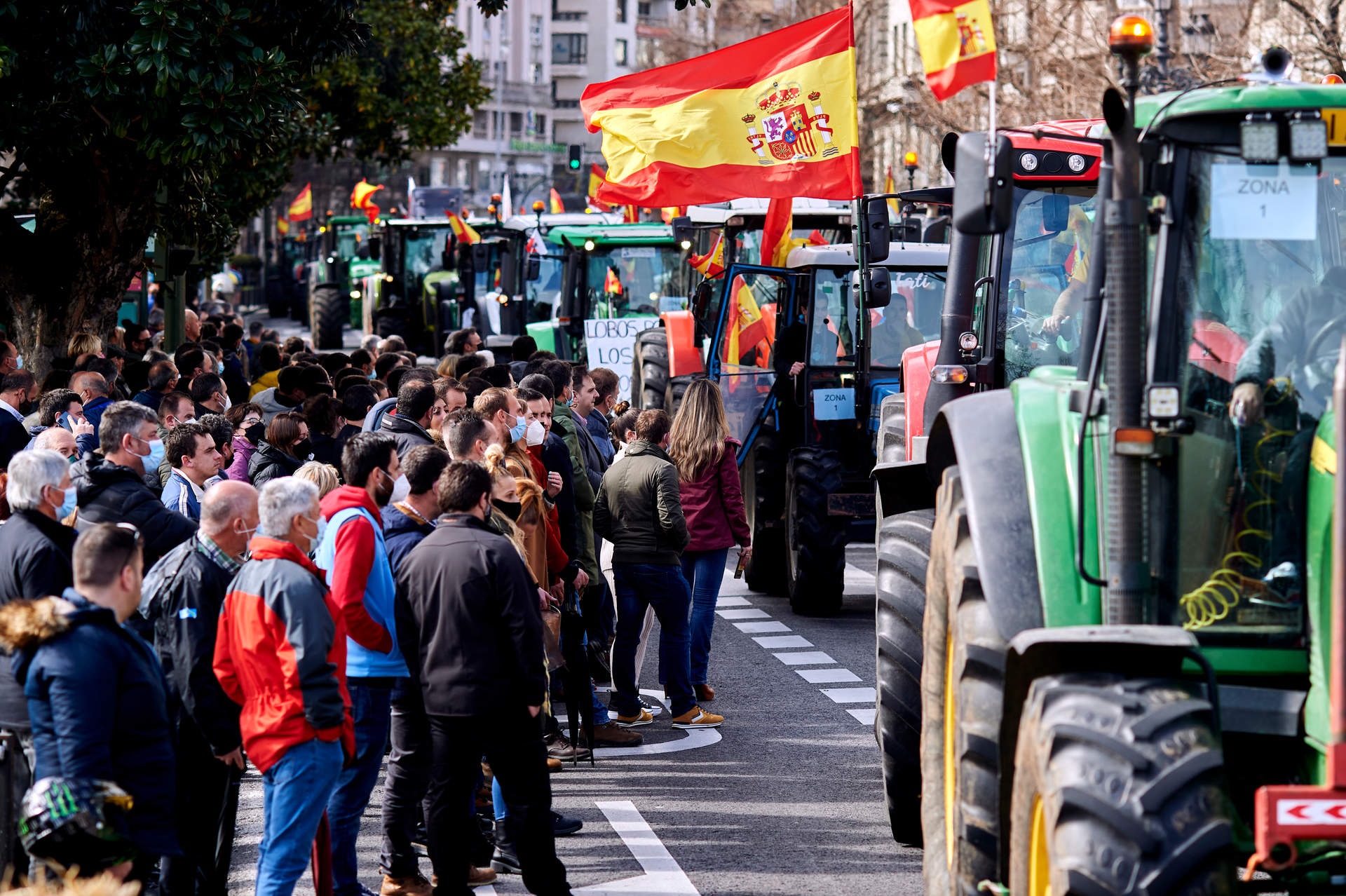 Manifestantes y tractores, con pancartas y banderas de España, en una marcha.
