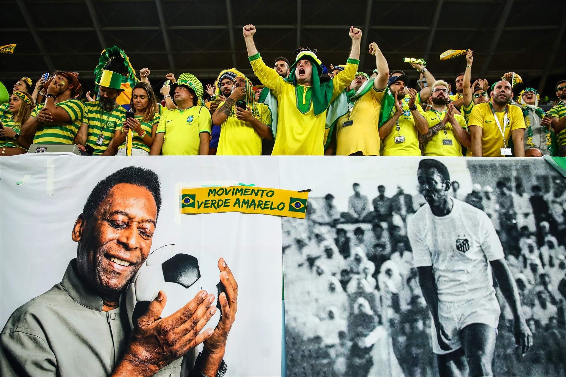 Los seguidores brasileños muestran una pancarta con la imagen de la leyenda del fútbol brasileño Pelé y un mensaje de pronta recuperación.