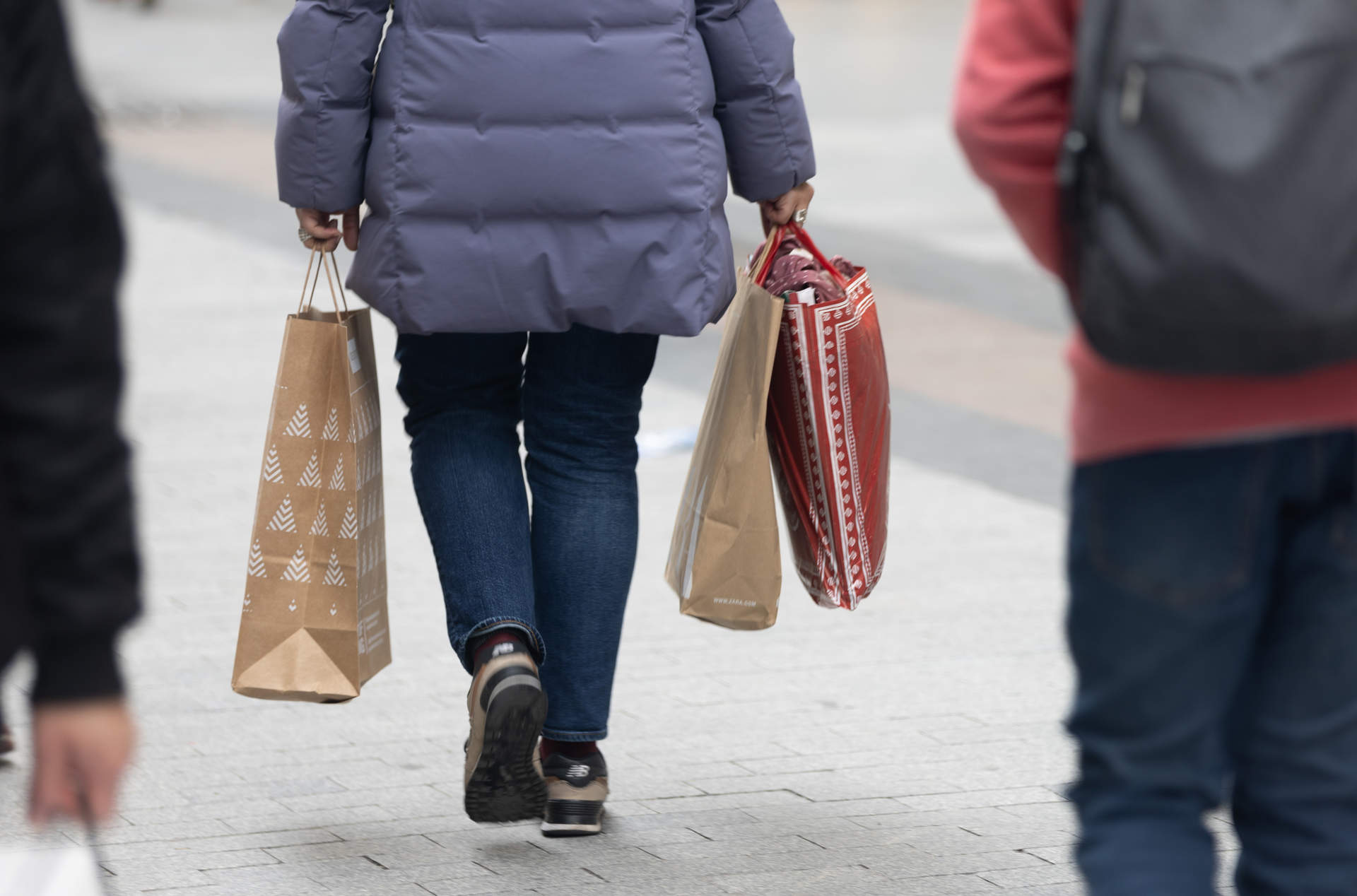 Una persona sujeta varias bolsas con compras de Navidad