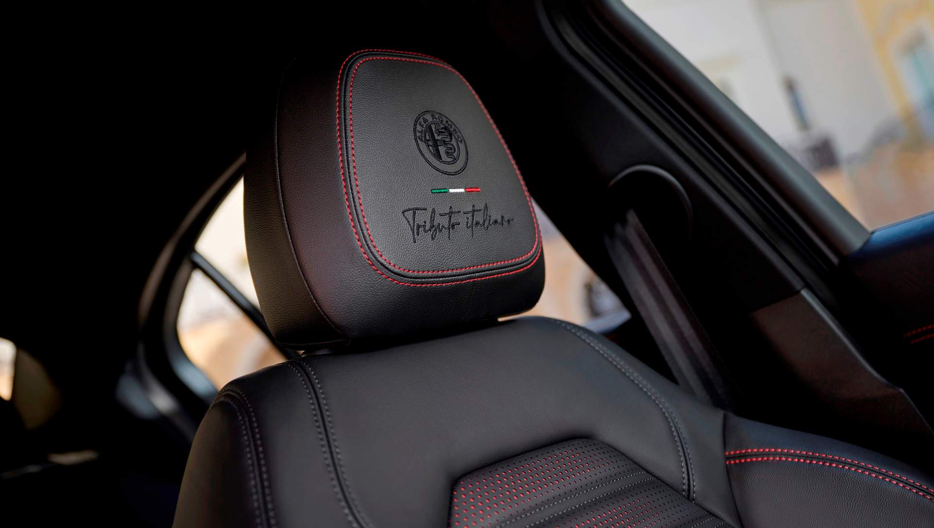 Los reposacabezas delanteros llevan bordados el logo “Tributo italiano”. A destacar los puntos rojos en los asientos de cuero negro.