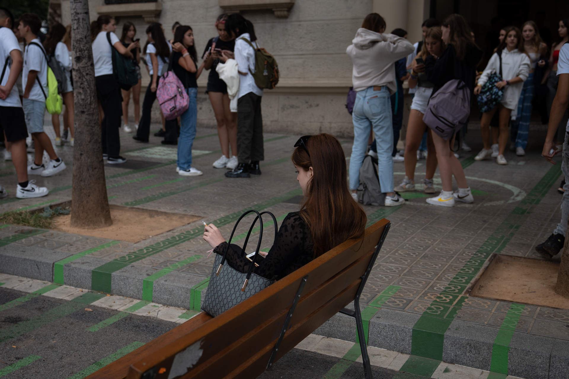 Una joven fuma sentada en un banco a la salida de un colegio (Foto: David Zorrakino / Europa Press)